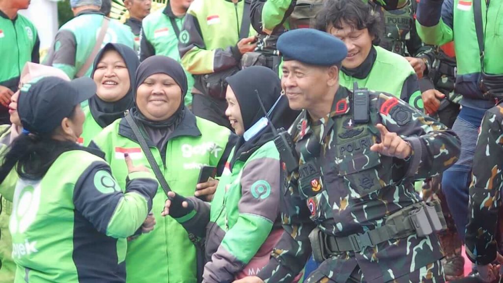 Seorang personel Brimob Polda Bali menari bersama pengemudi ojek online dalam acara peringatan HUT Brimob ke-80.