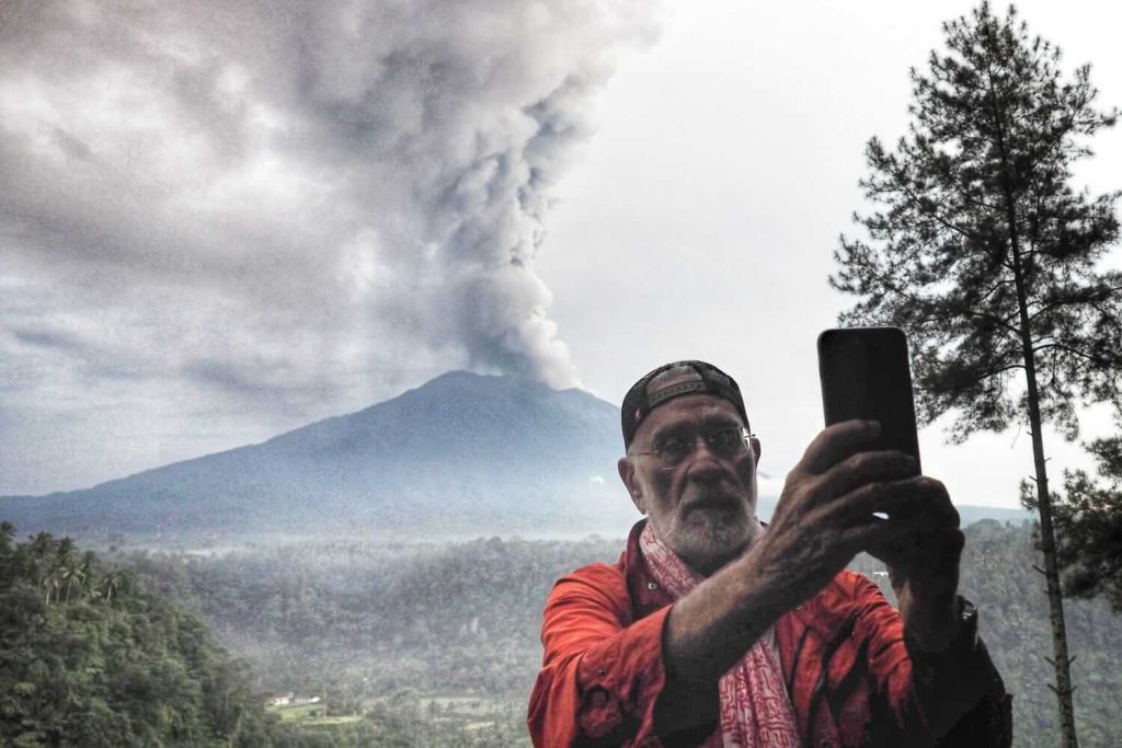 Seorang turis memotret Gunung Agung yang sedang erupsi dari sebuah restoran di Desa Rendang, Karangasem, Bali, 28 November 2017.
