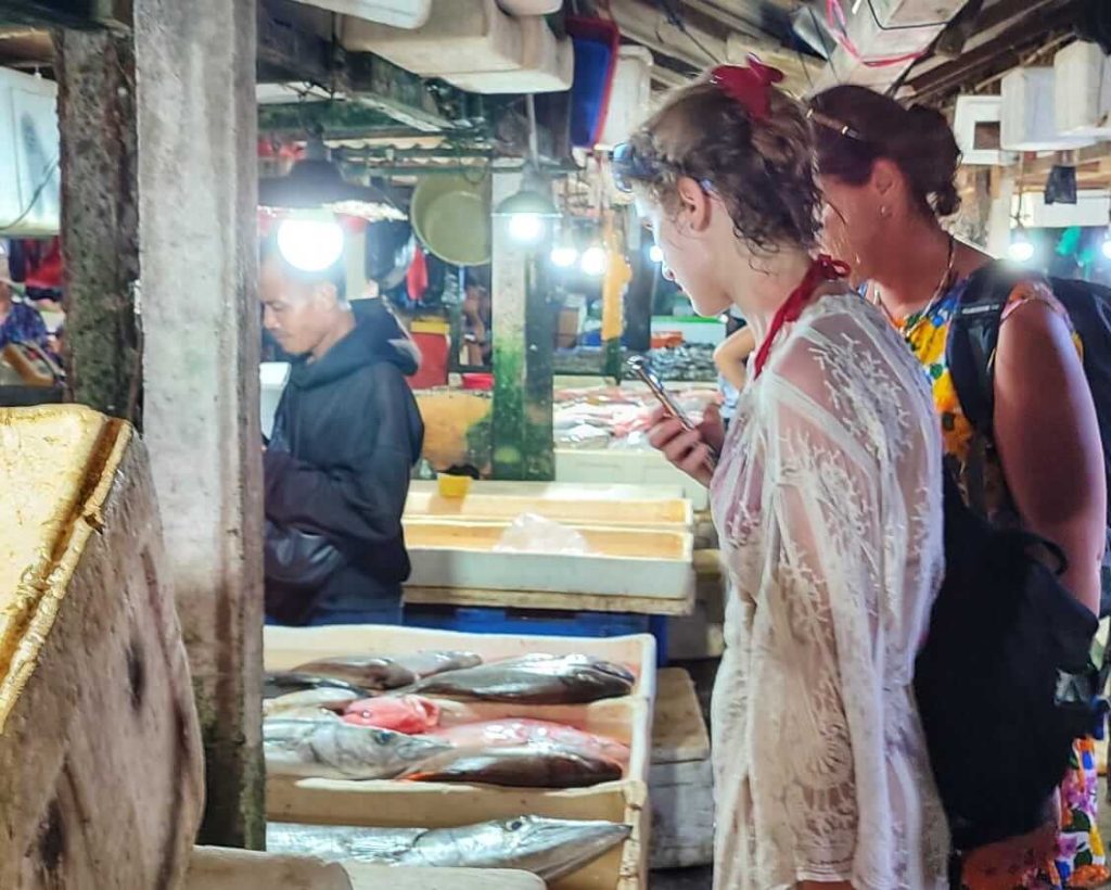 Dua turis menawar ikan segar kepada pedagang di Pasar Ikan Kedonganan.