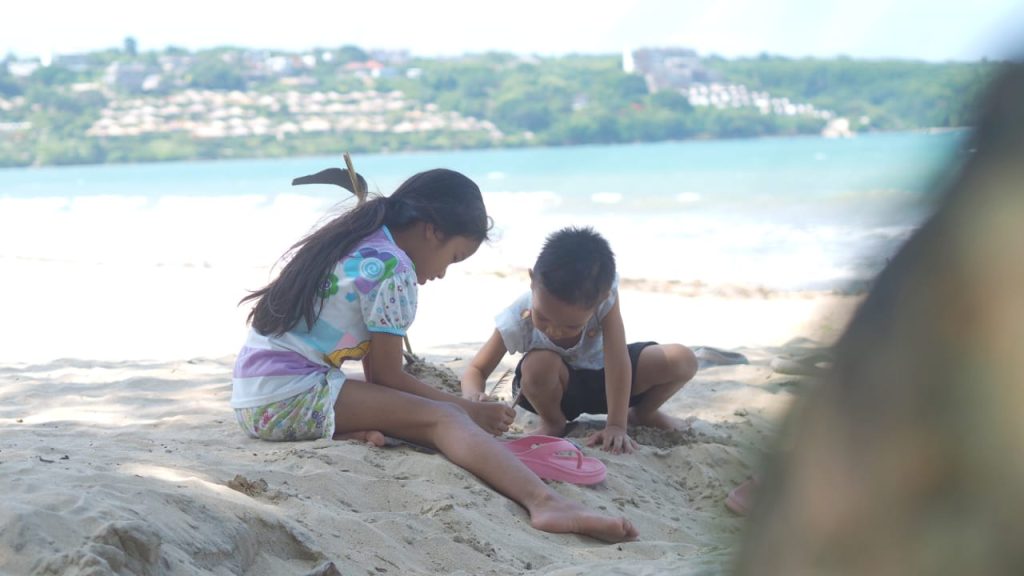 Anak-anak bermain pasir di pantai sebagai momen keseharian sederhana yang sarat makna.