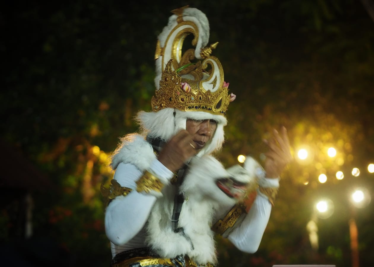 Seorang seniman Bali bernama Nyoman menampilkan aksi seni dengan api, memperlihatkan ekspresi penuh tawa dan keteguhan hati.