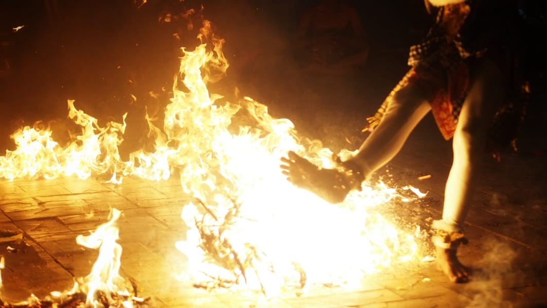 Penari yang memerankan Hanoman dalam pertunjukan tradisional Bali sedang beraksi di panggung.