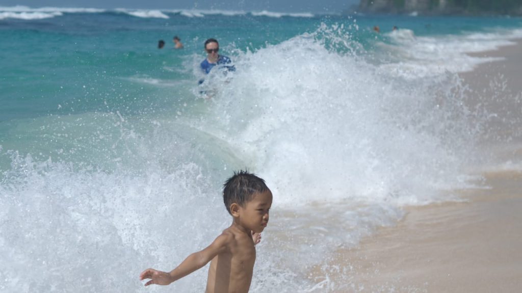 Anak belajar kewaspadaan dan refleks di pantai melalui interaksi dengan ombak dan ritme laut.