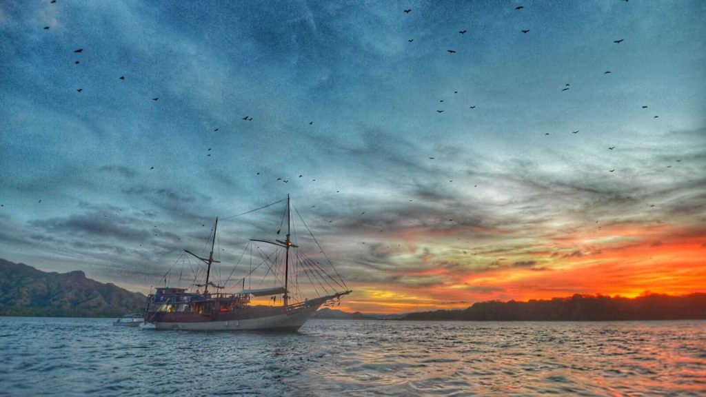 Wisata berlayar dengan kapal pinisi di Labuan Bajo menyusuri pulau-pulau eksotis dengan suasana laut yang tenang dan biru.