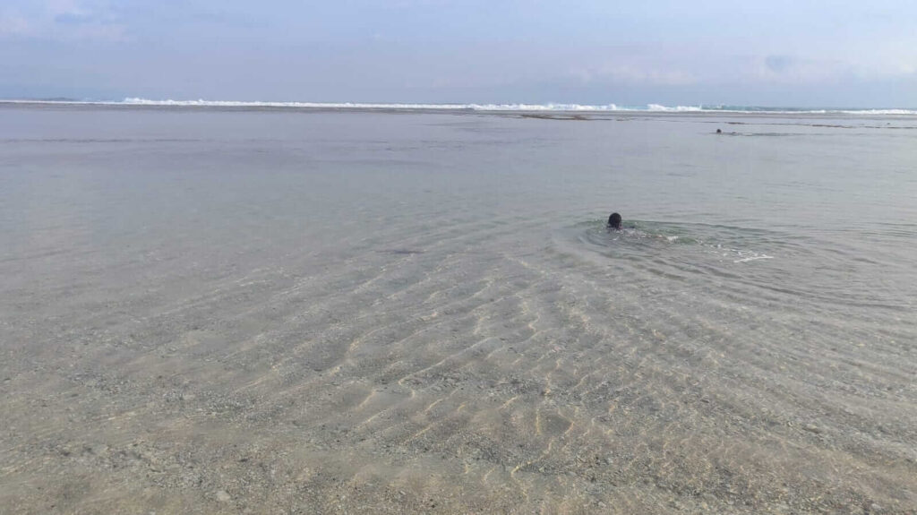 Air laut jernih di Pantai Timbis dengan dasar laut dangkal terlihat dari permukaan.
