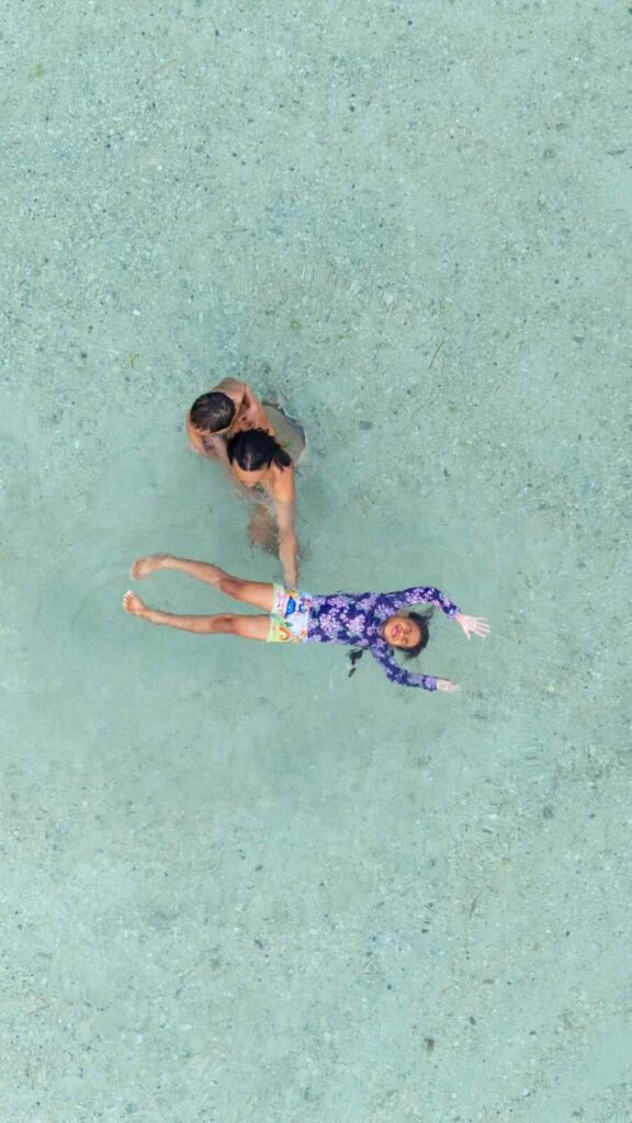 Hendra bermain bersama anak-anaknya di pantai dengan suasana ceria.