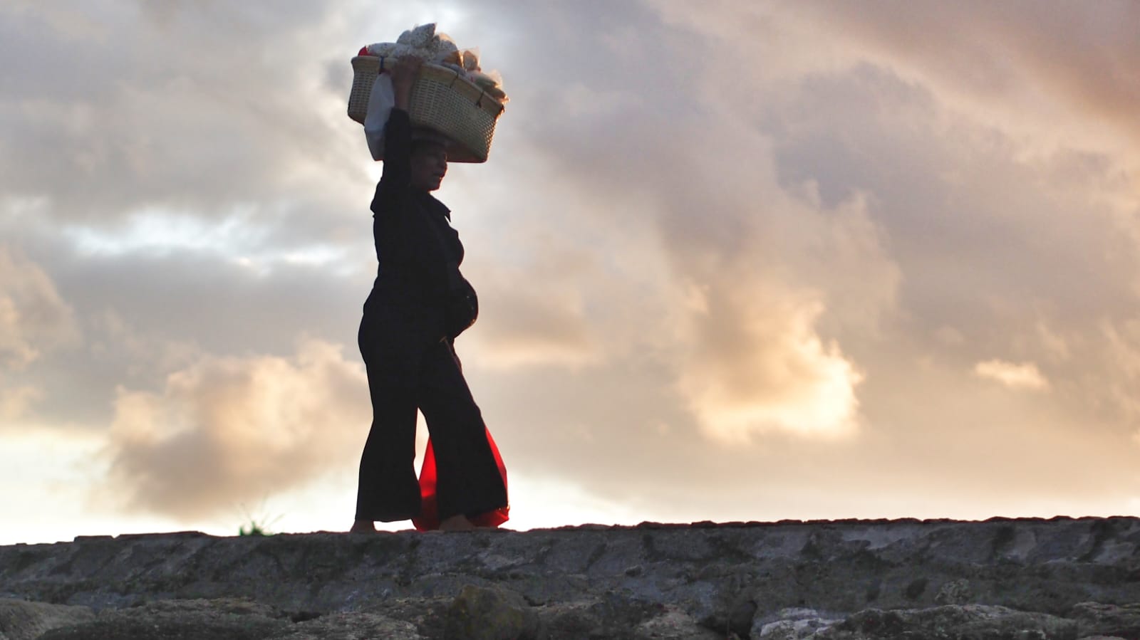 Seorang perempuan beraktivitas di ruang keseharian yang sederhana dengan ekspresi penuh keteguhan.