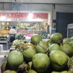 Tumpukan kelapa muda siap dijual di sebuah warung sederhana.