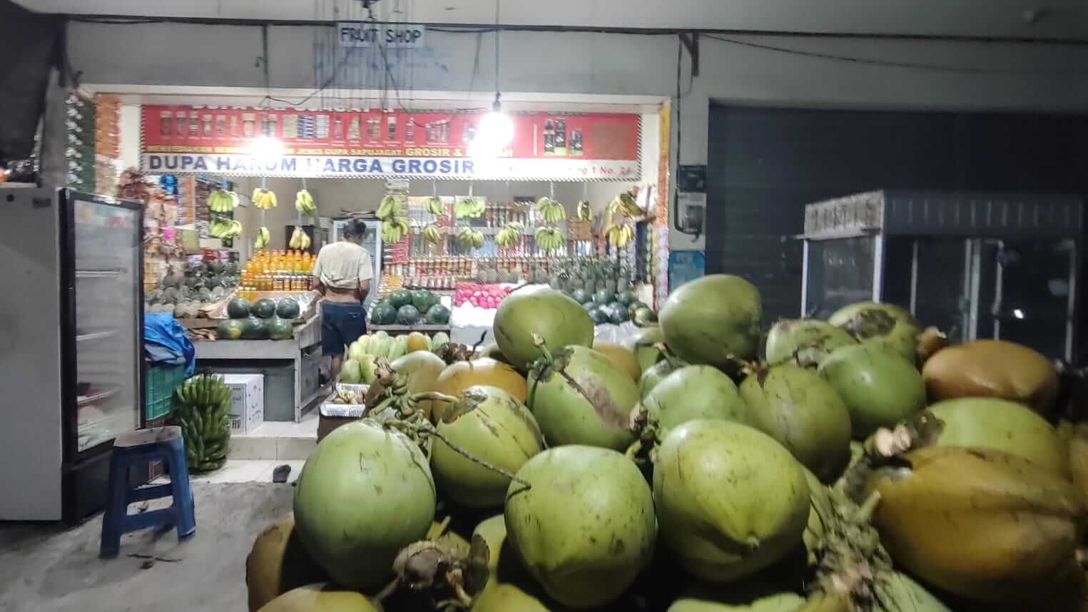 Tumpukan kelapa muda siap dijual di sebuah warung sederhana.