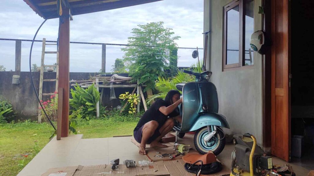 Sebuah Vespa klasik terparkir, menampilkan detail yang terawat dengan baik.