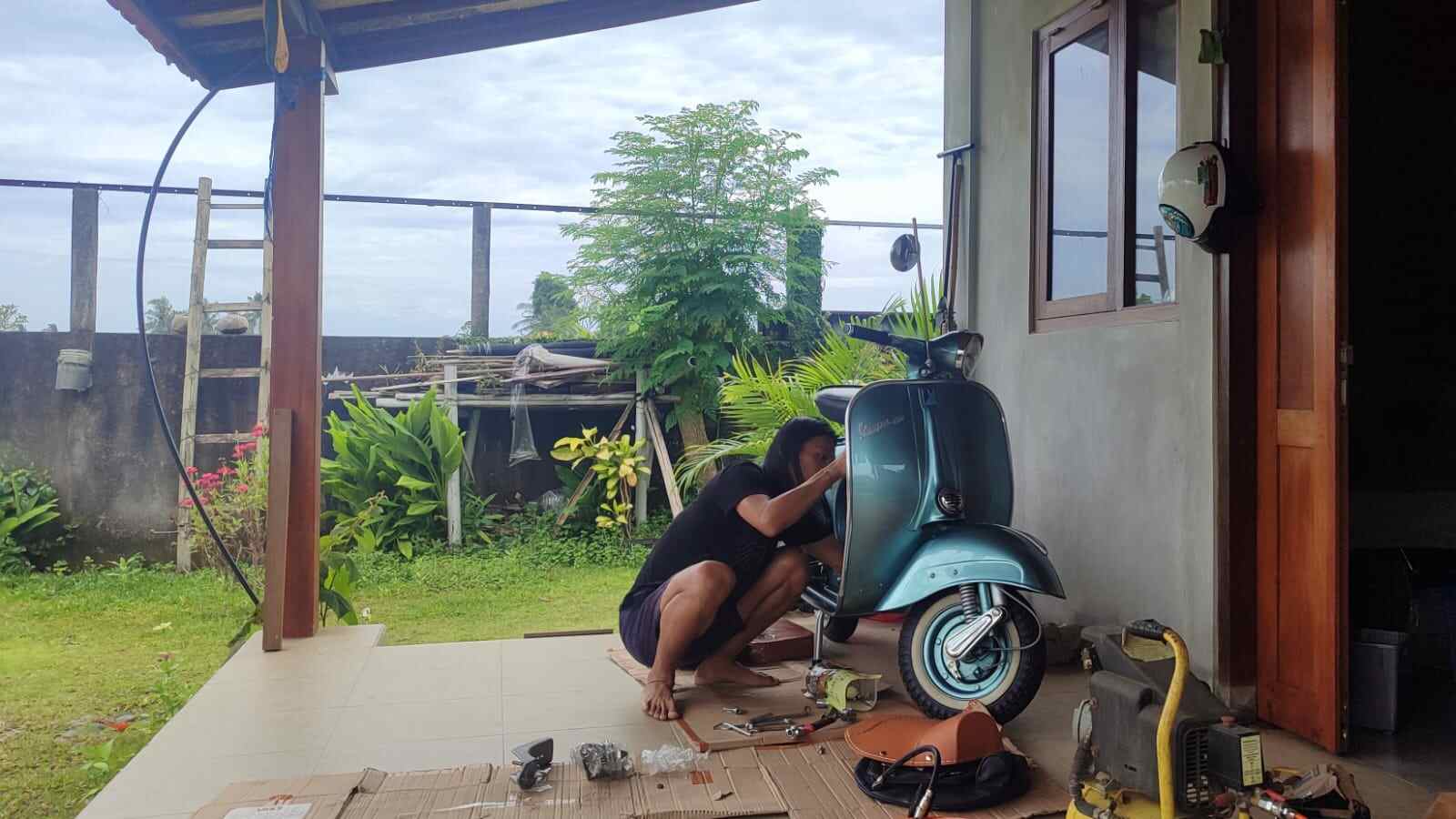 Sebuah Vespa klasik terparkir, menampilkan detail yang terawat dengan baik.