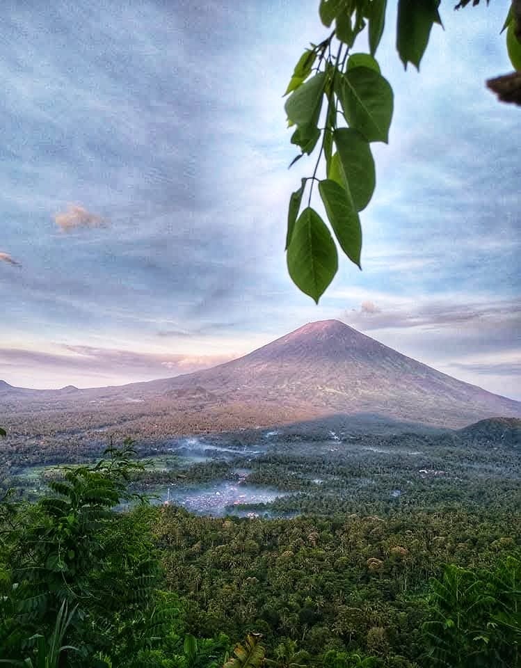 Gunung menjulang di kejauhan, melambangkan perjalanan dan keberanian mendekat.