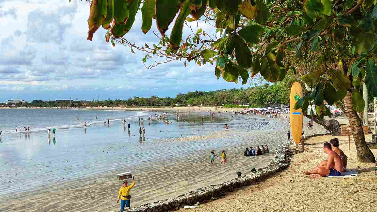 Suasana Pantai Muaya Jimbaran dengan aktivitas warga dan wisatawan di tepi laut.