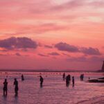 Suasana Pantai Melasti saat air surut dengan langit senja berwarna gradasi.