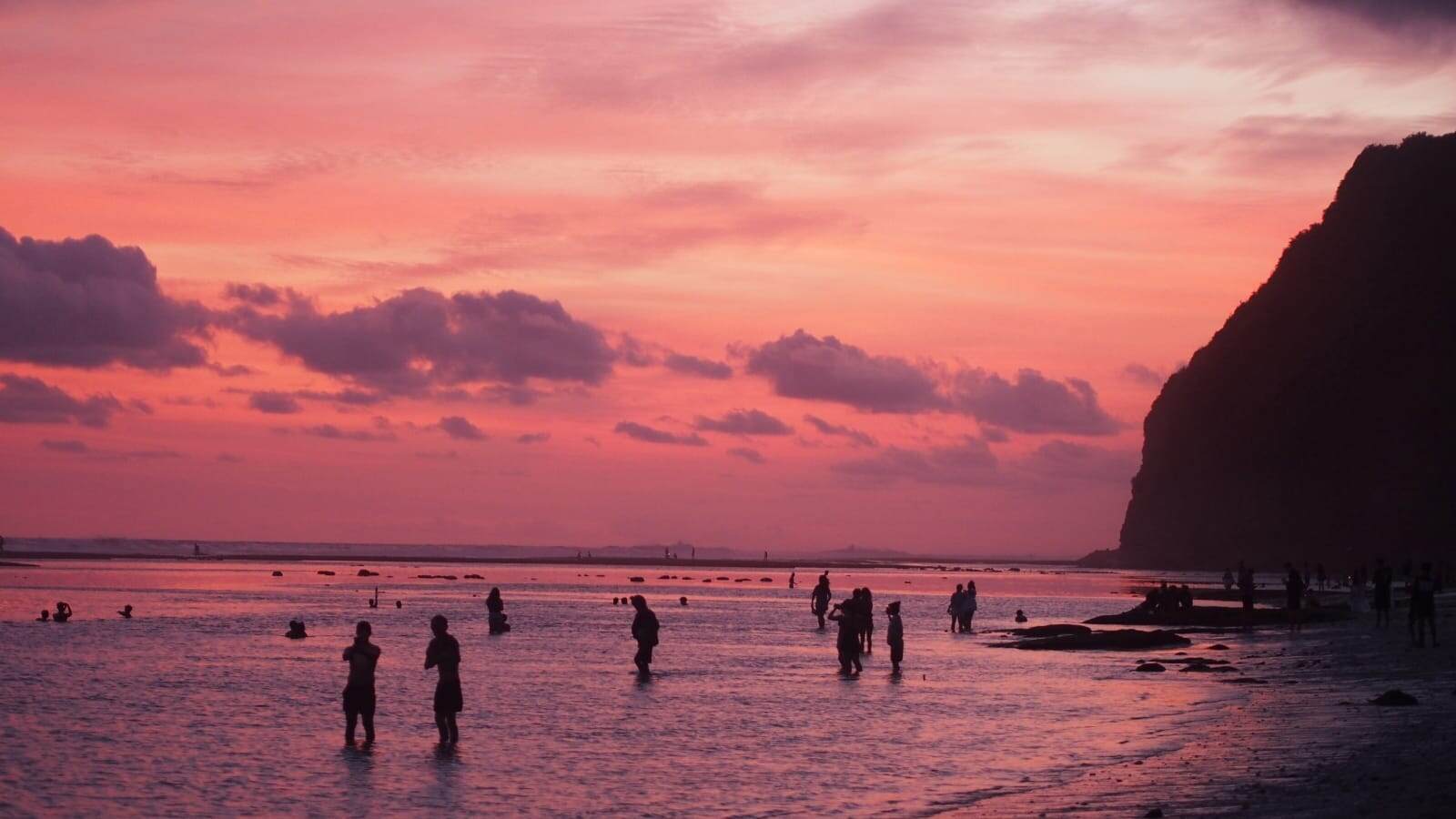 Suasana Pantai Melasti saat air surut dengan langit senja berwarna gradasi.