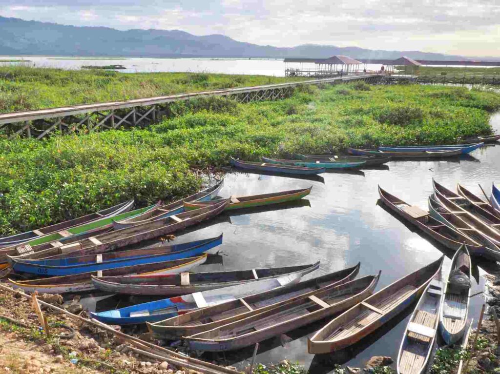 Perahu-perahu bersandar di tepian danau saat senja.