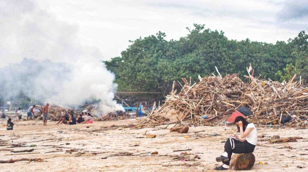 Warga membakar tumpukan sampah kayu dan bambu di pesisir Pantai Kedonganan.