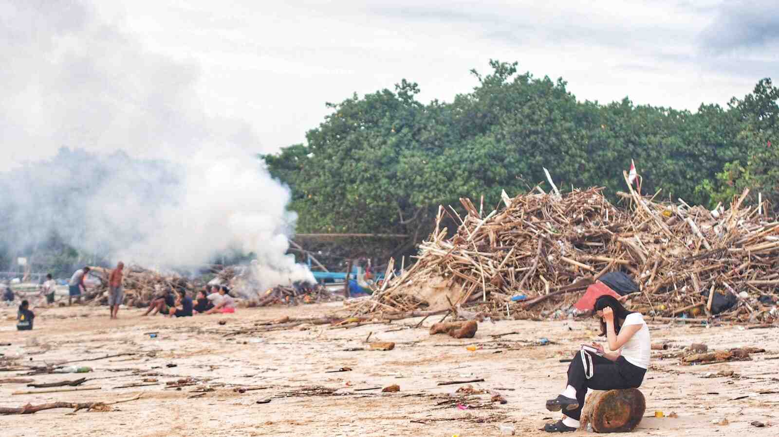 Warga membakar tumpukan sampah kayu dan bambu di pesisir Pantai Kedonganan.
