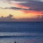Suasana senja di Pantai Kuta dengan orang-orang menikmati pemandangan.
