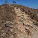 Seseorang melangkah maju dengan latar pemandangan yang mengarah ke puncak.
