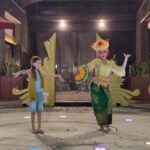 Seorang anak berinteraksi langsung dengan tradisi lokal dalam suasana budaya yang autentik