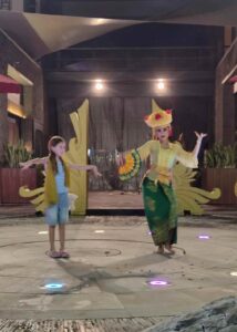 Seorang anak berinteraksi langsung dengan tradisi lokal dalam suasana budaya yang autentik