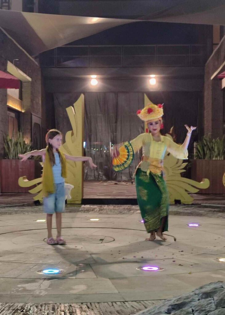 Seorang anak berinteraksi langsung dengan tradisi lokal dalam suasana budaya yang autentik