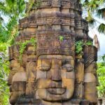 Ukiran empat wajah dari batu dengan detail artistik dan nuansa budaya yang kuat