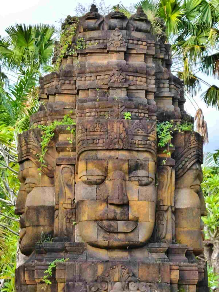 Ukiran empat wajah dari batu dengan detail artistik dan nuansa budaya yang kuat