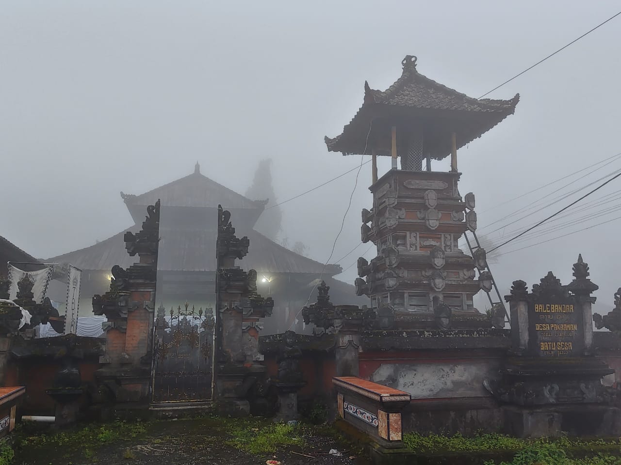 Kabut menyelimuti desa adat di pegunungan Bali dengan arsitektur tradisional dan suasana tenang