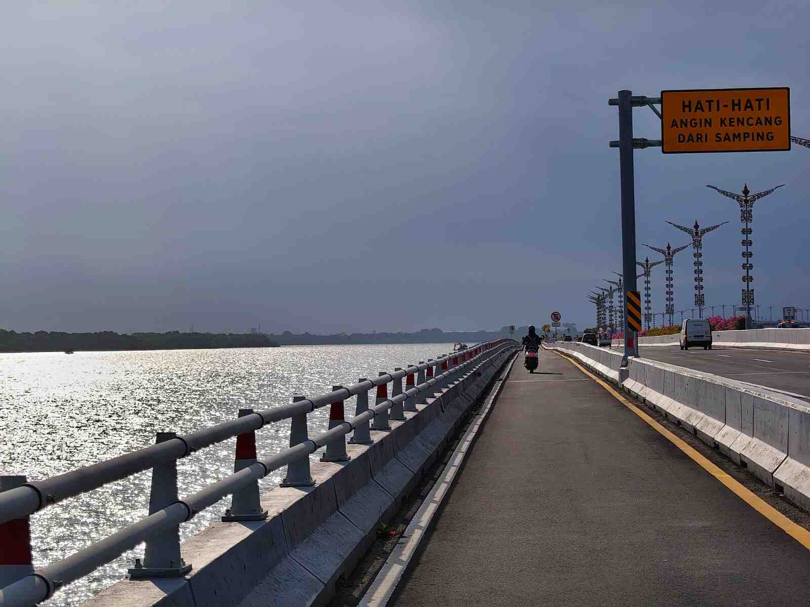 Pemandangan Jalan Tol Bali Mandara dengan perpaduan cahaya matahari dan langit mendung
