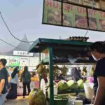 Deretan stan kuliner di sepanjang akses menuju area pertunjukan dengan pengunjung menikmati makanan dan minuman di kawasan acara.