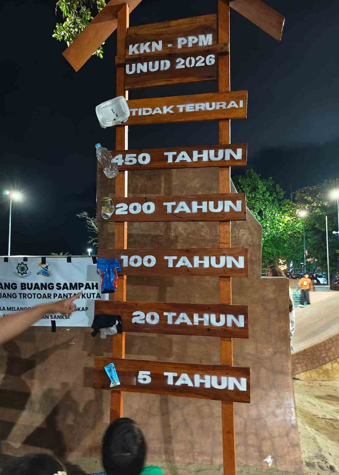 Papan informasi edukasi waktu penguraian sampah di Pantai Kuta, Badung tentang pentingnya menjaga lingkungan