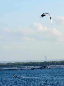 Para kitesurfer meluncur di atas ombak memanfaatkan hembusan angin di lautan