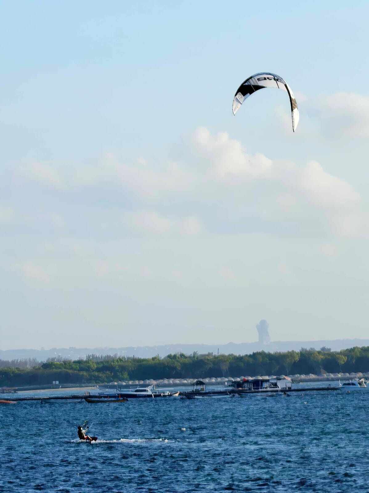 Para kitesurfer meluncur di atas ombak memanfaatkan hembusan angin di lautan