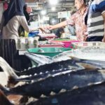 Wisatawan mancanegara bertransaksi dengan pedagang ikan di Pasar Ikan Kedonganan