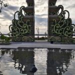 Arsitektur modern berpadu ornamen Bali dan lanskap tropis dengan pantulan air.