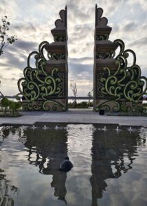 Arsitektur modern berpadu ornamen Bali dan lanskap tropis dengan pantulan air.