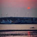 Kapal besar dan perahu kecil di bawah langit senja.