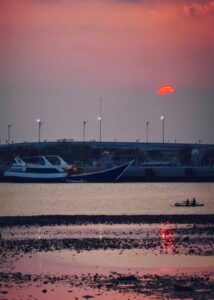 Kapal besar dan perahu kecil di bawah langit senja.