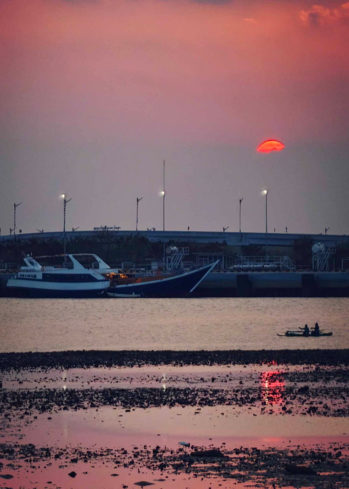 Kapal besar dan perahu kecil di bawah langit senja.