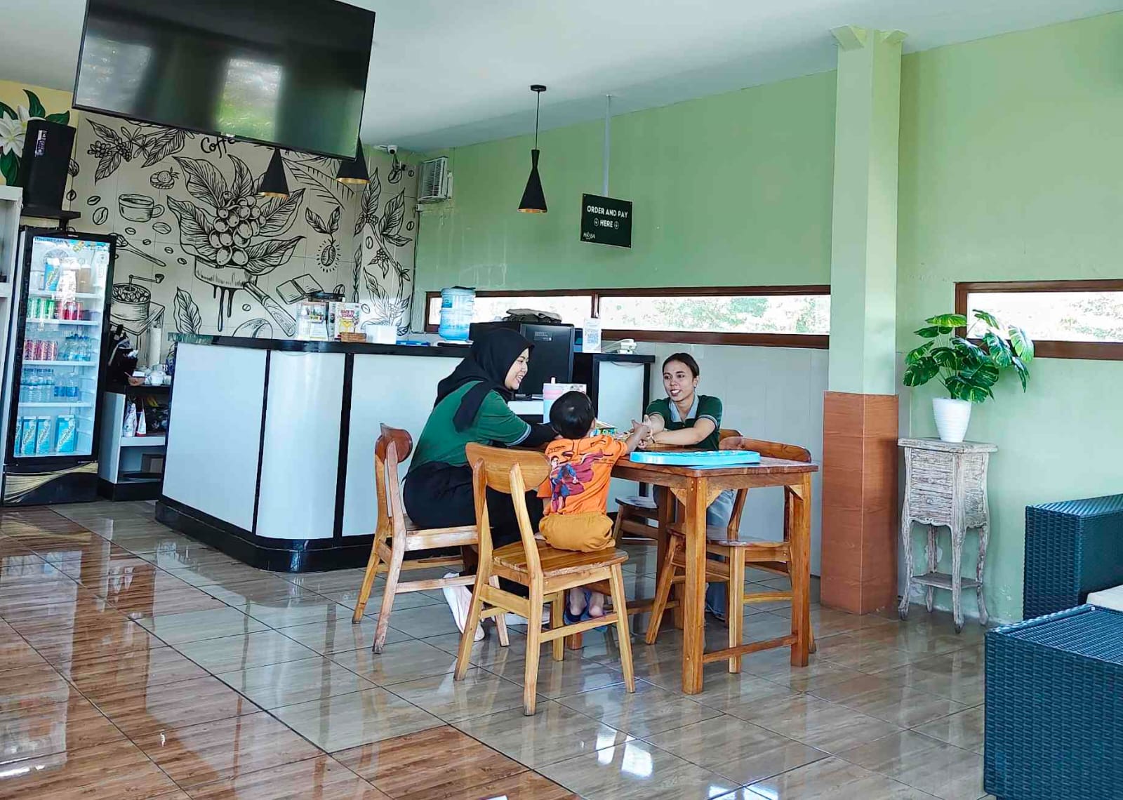 Staf Hanza Cafe mengajak anak bermain di sela kesibukan melayani pelanggan.