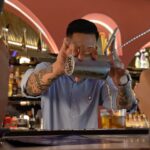 Bartender bekerja menyiapkan minuman di area bar.