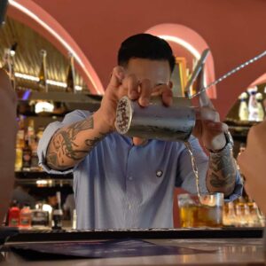 Bartender bekerja menyiapkan minuman di area bar.