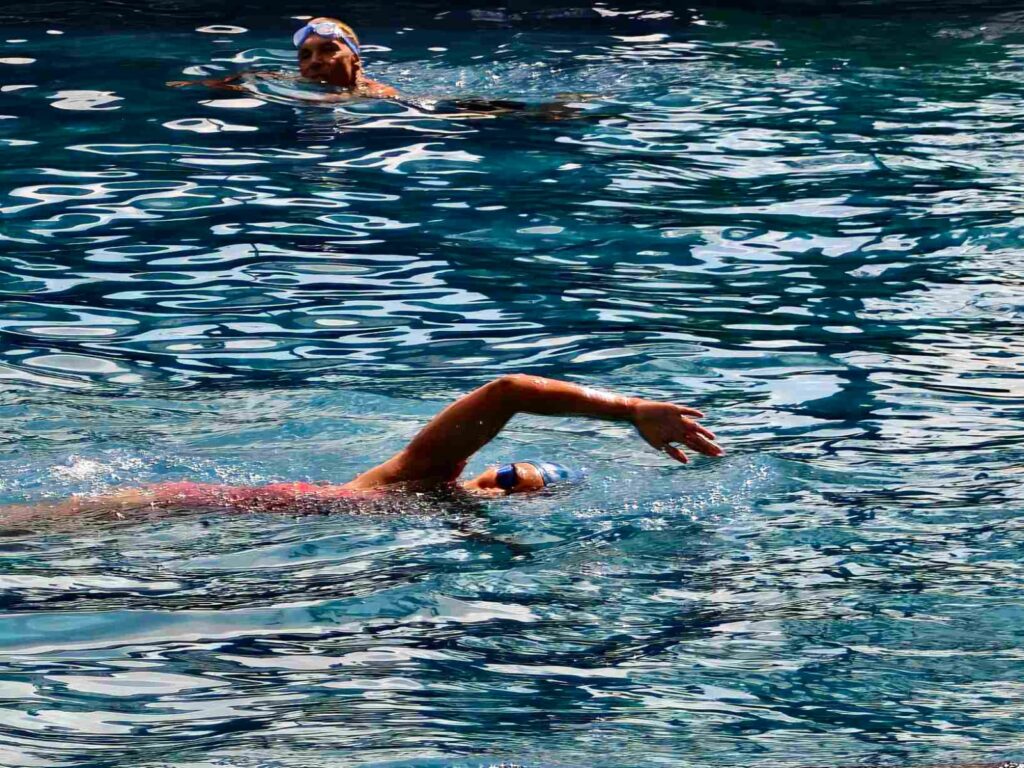 Orang berenang di kolam sebagai aktivitas olahraga dan rekreasi.