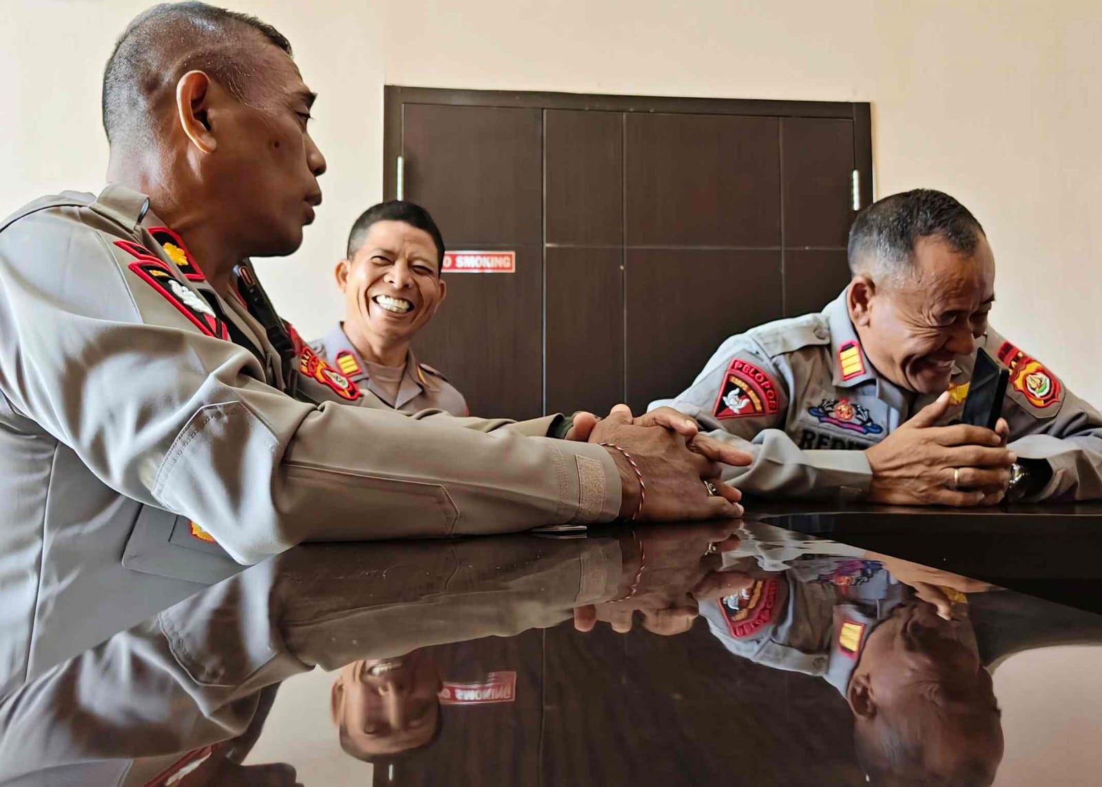 Personel berseragam tersenyum sebagai gambaran sisi manusiawi di balik tugas.