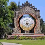 Gong Perdamaian Dunia dengan patung tokoh dunia, deretan bendera negara, dan simbol keberagaman agama.