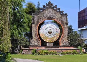 Gong Perdamaian Dunia dengan patung tokoh dunia, deretan bendera negara, dan simbol keberagaman agama.