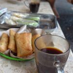 Secangkir kopi dan sepiring lumpia dalam suasana hangat dan menenangkan.