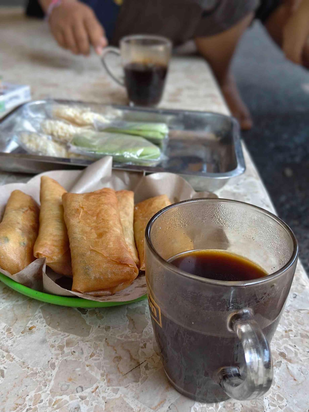 Secangkir kopi dan sepiring lumpia dalam suasana hangat dan menenangkan.